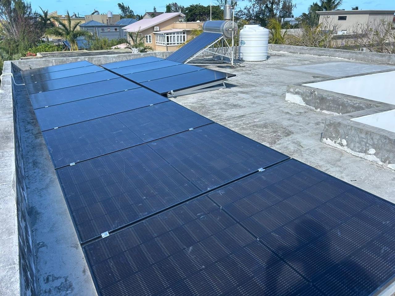 Photovoltaic panels installed on a flat concrete roof in Mauritius beside a solar water heater
