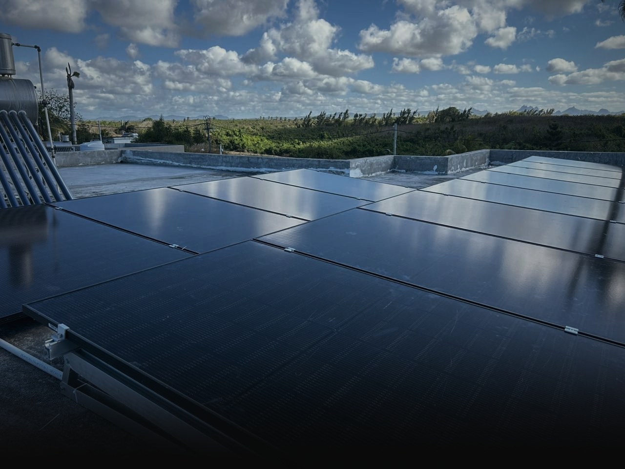 Solar panels flush-mounted across a flat concrete roof in Mauritius under a wide sky