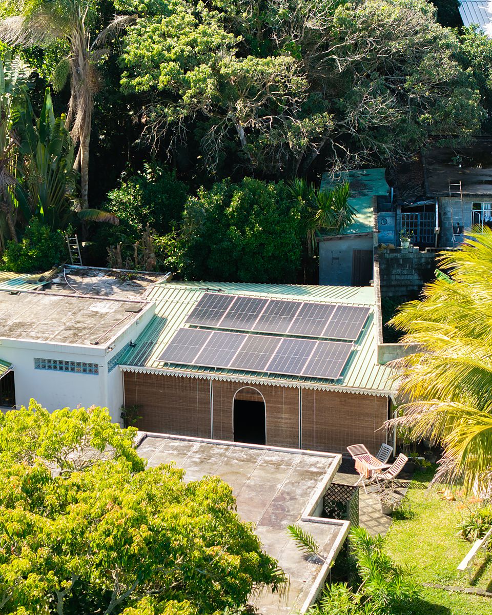 Bifacial solar panels on the inclined tin roof of a Mauritian family home