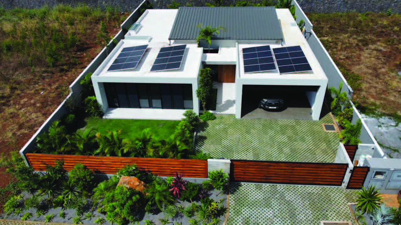 Aerial view of a modern flat-roof villa in Mauritius with rooftop solar arrays